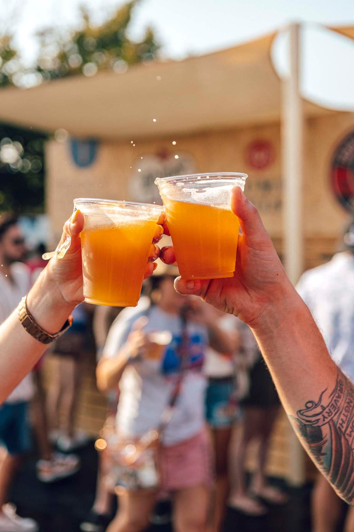 two hands holding beers coming together in a toast 