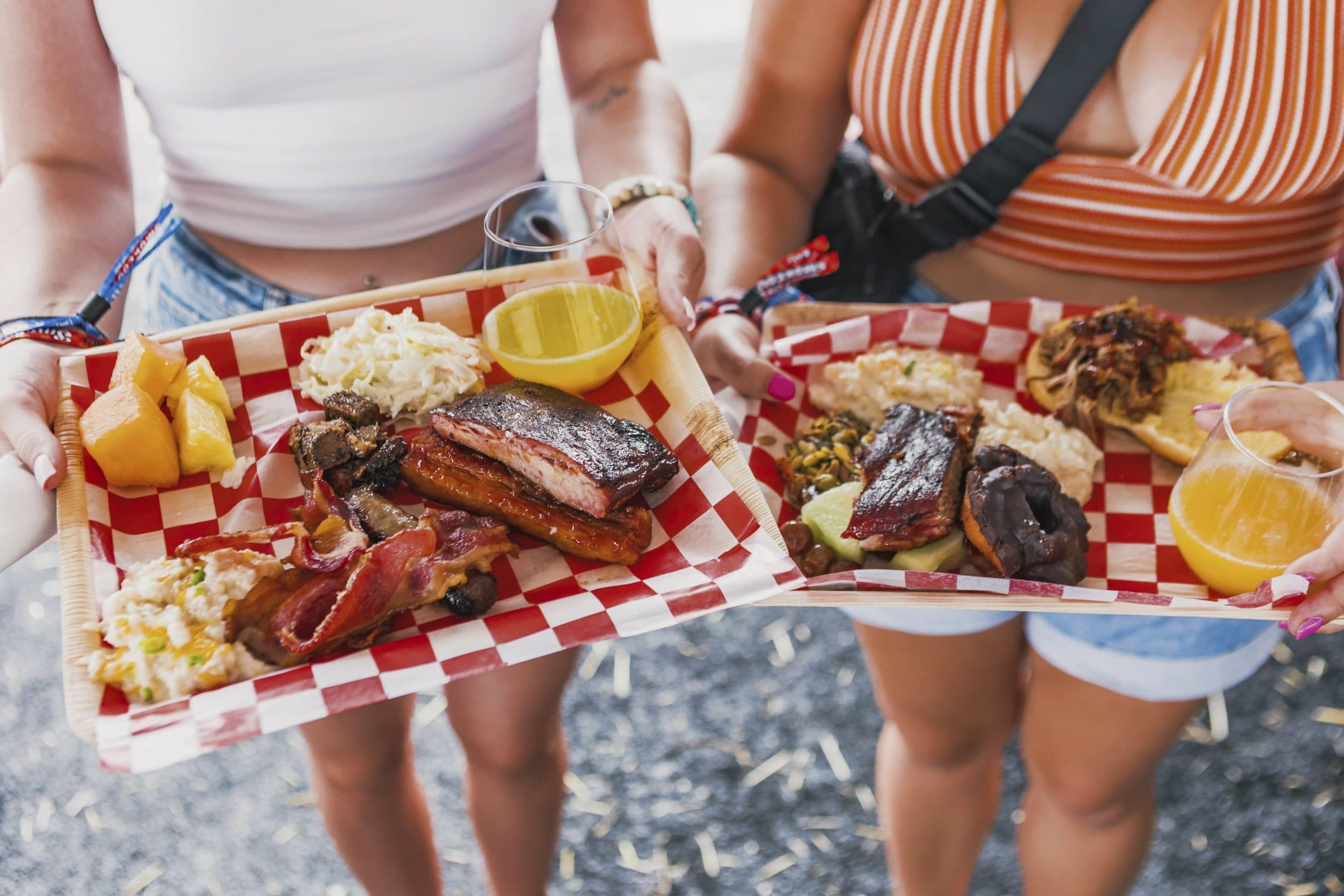 two girls holding trays of BBQ and drinks
