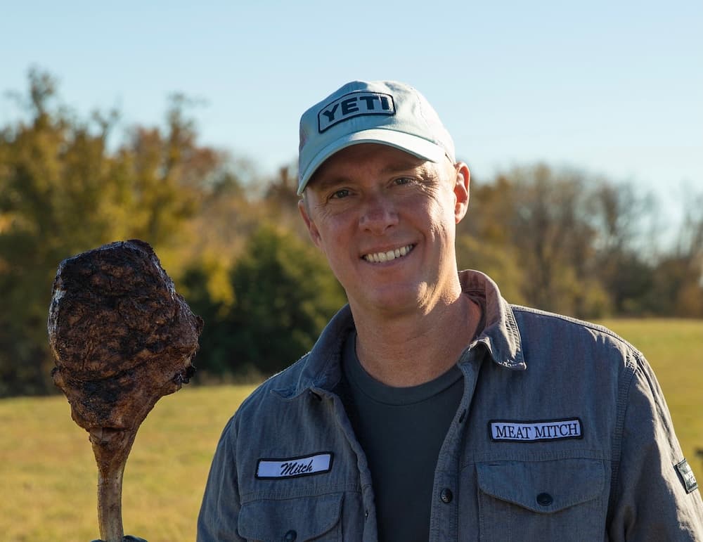 a guy named mitch smiling while holding a steak
